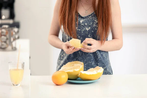 Beautiful young woman with citrus fruits in kitchen — Stock Photo, Image