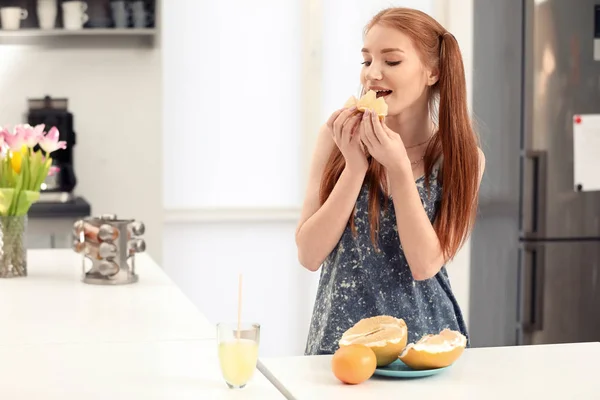 Hermosa mujer joven comiendo cítricos en la cocina —  Fotos de Stock