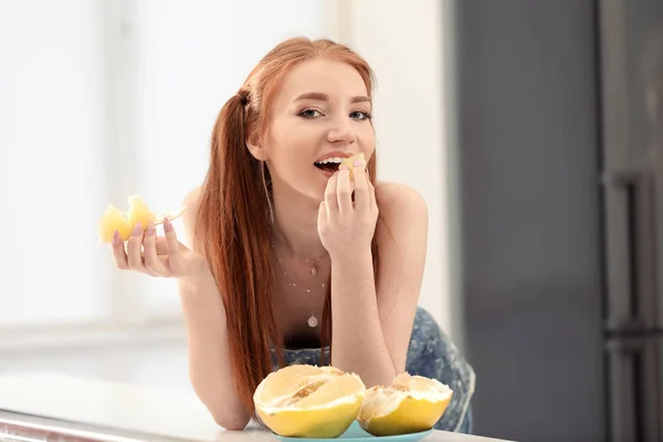 Mulher bonita comendo frutas cítricas na cozinha — Fotografia de Stock