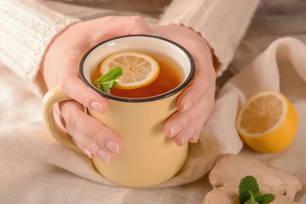 Woman holding mug of hot lemon tea with ginger at table — Stock Photo, Image