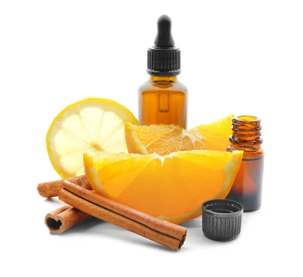 Flaska citrus eterisk olja, kanelstänger och frukter på vit bakgrund — Stockfoto