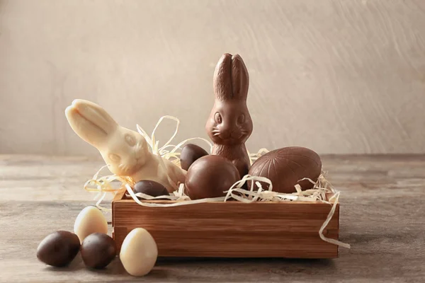 Chocolate Easter bunnies and eggs in crate on table — Stock Photo, Image