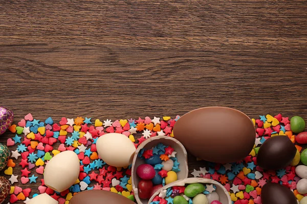Composición con huevos de Pascua de chocolate, espolvoreos de colores y caramelos sobre fondo de madera — Foto de Stock