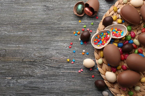 Ovos de Páscoa de chocolate, polvilhas coloridas e doces no fundo de madeira — Fotografia de Stock