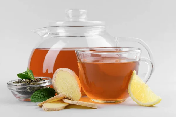 Hot beverage with mint, ginger and lemon in tea set on grey background — Stock Photo, Image