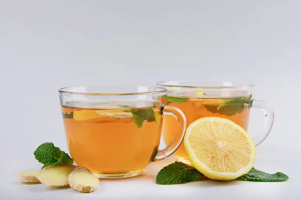 Tasses de thé délicieux à la menthe, au gingembre et au citron sur fond gris — Photo