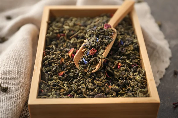 Trälåda och scoop med torr gröna teblad på bord — Stockfoto
