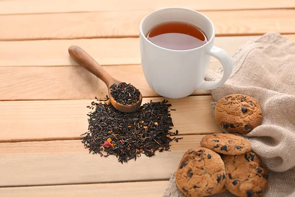 Torr svart te blad, cookies och kopp aromatisk dryck på bord — Stockfoto