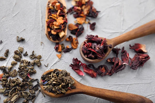 Spoons with different types of dry tea leaves on light background — Stock Photo, Image