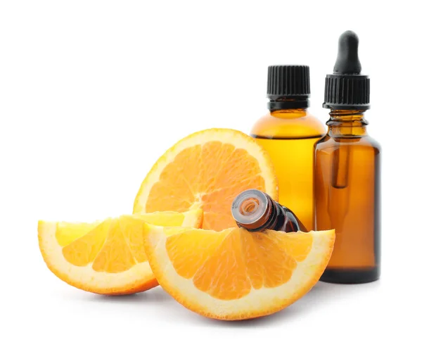 Flaskor med citrus eterisk olja och skivad frukt på vit bakgrund — Stockfoto