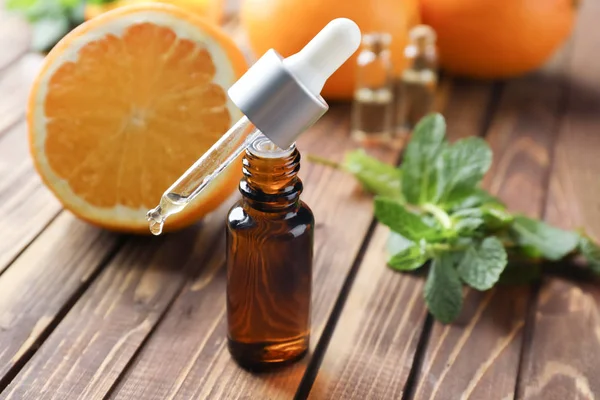 Bottle and dropper with citrus essential oil on wooden table — Stock Photo, Image