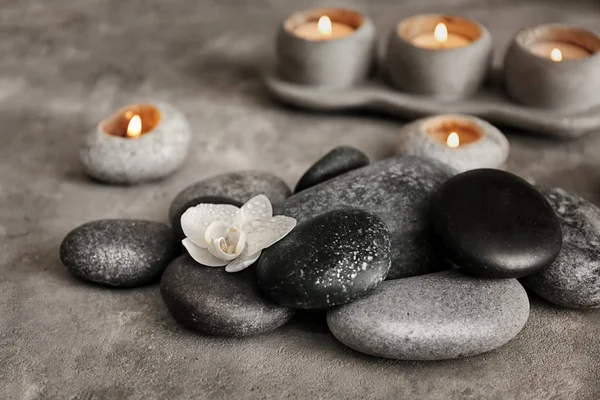 Piedras de spa y hermosa flor de orquídea en mesa gris — Foto de Stock