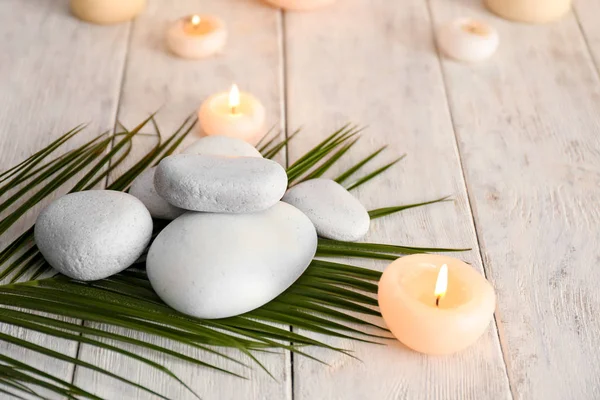 Beautiful composition with spa stones and candles on wooden table — Stock Photo, Image