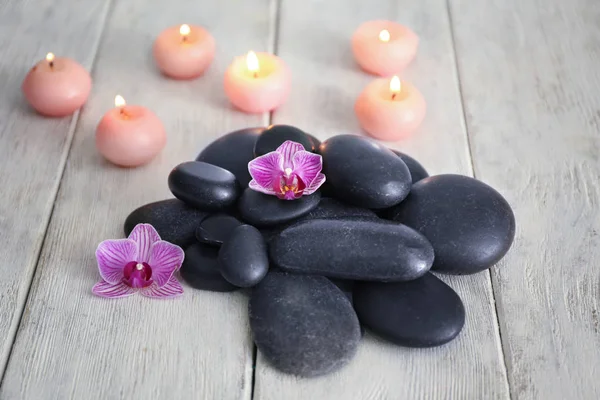 Spa stones, flowers and burning candles on wooden background — Stock Photo, Image