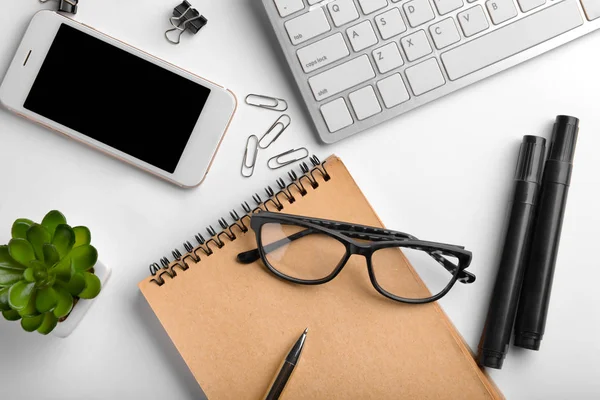 Workplace table composition with computer keyboard, smartphone and stationery on white background — Stock Photo, Image