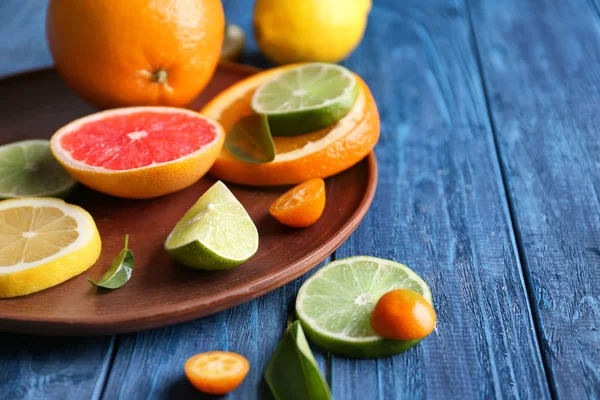 Plate with fresh citrus fruits on wooden table — Stock Photo, Image