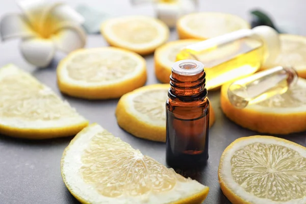 Бутылка цитрусового эфирного масла и ломтики лимона на столе — стоковое фото