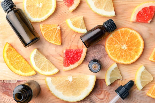 Bottles of essential oil and citrus slices on wooden table — Stock Photo, Image