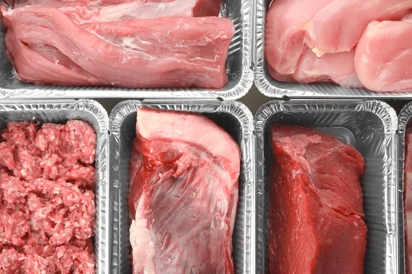 Raw meat in foil containers, closeup — Stock Photo, Image