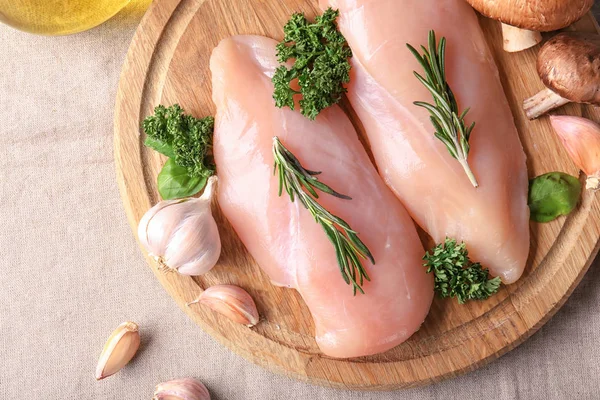 Raw chicken fillet with herbs on wooden board — Stock Photo, Image