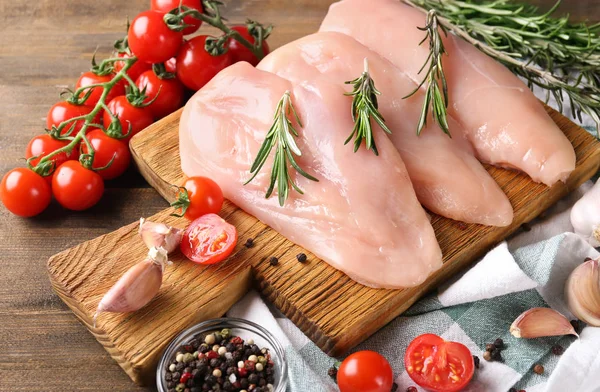 Composition with raw chicken fillet on wooden table