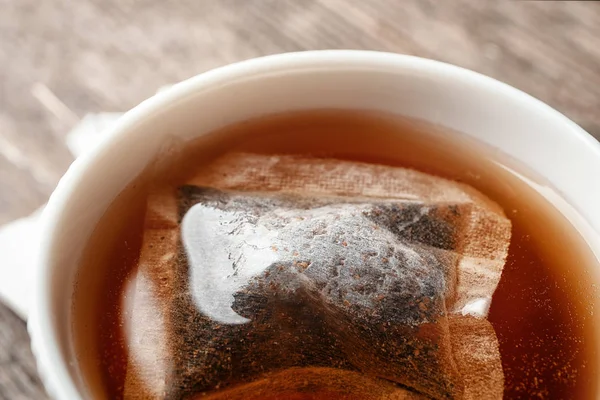 Becher mit heißem Tee und Teebeutel auf dem Tisch, Nahaufnahme — Stockfoto