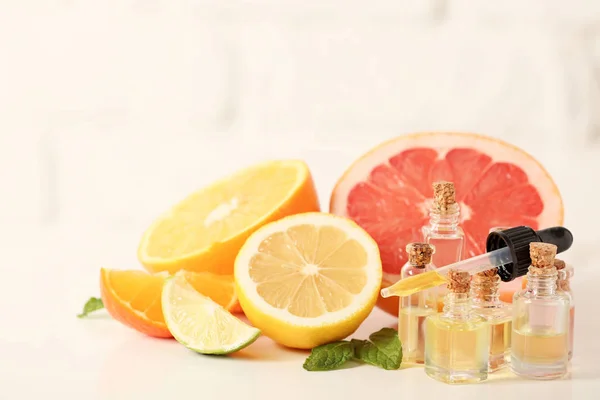 Bottles with essential oils and citrus fruits on white table — Stock Photo, Image