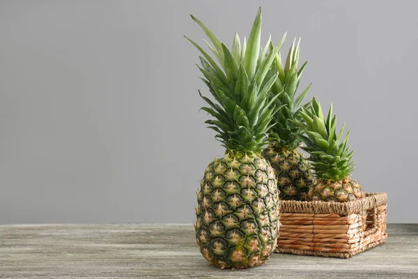 Čerstvé zralé ananasy na stole šedé pozadí — Stock fotografie