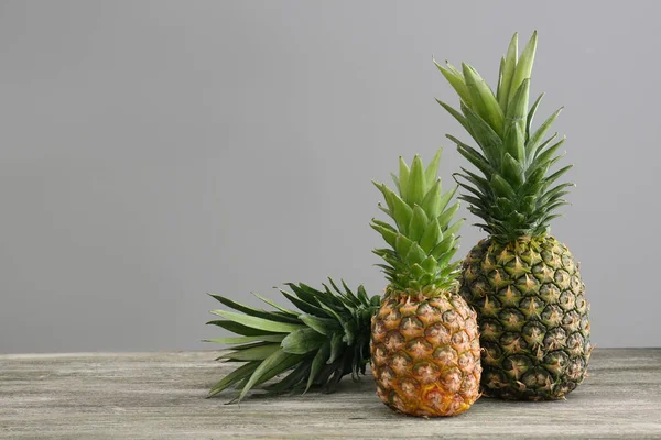 Fresh ripe pineapples on table against grey background — Stock Photo, Image