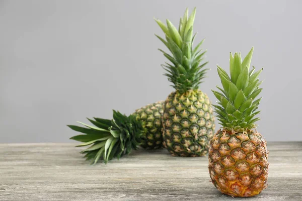 Čerstvé zralé ananasy na stole šedé pozadí — Stock fotografie