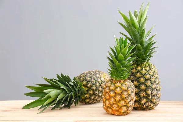 Ananasy dojrzałe na stole na szarym tle — Zdjęcie stockowe