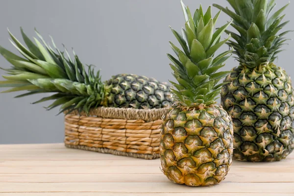Ananasy dojrzałe na stole na szarym tle — Zdjęcie stockowe