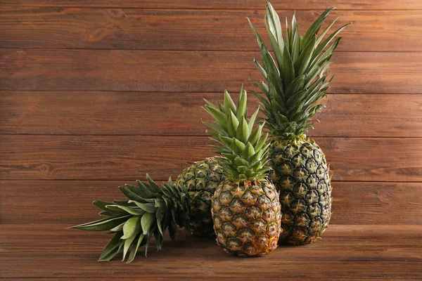 Čerstvé zralé ananasy na dřevěné pozadí — Stock fotografie