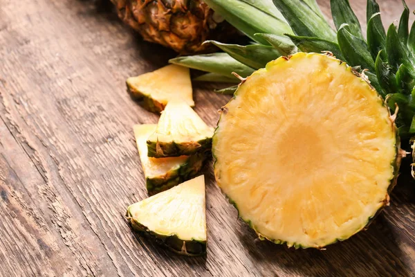 Cut ripe pineapples on wooden background — Stock Photo, Image