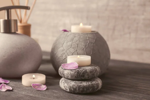 Piedras de spa con velas y cosméticos sobre mesa de madera — Foto de Stock