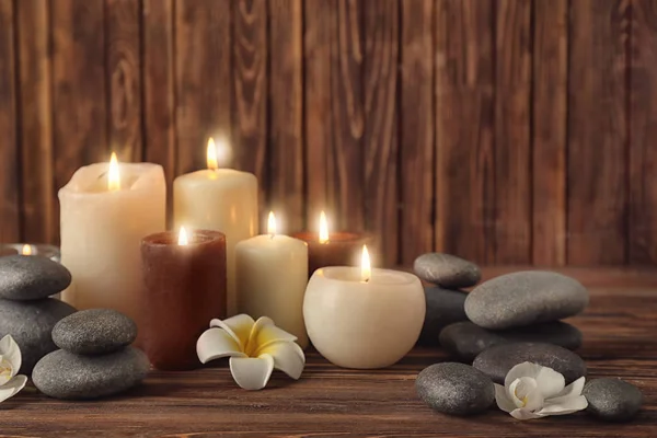Svíčky s wellness kameny na dřevěné pozadí — Stock fotografie