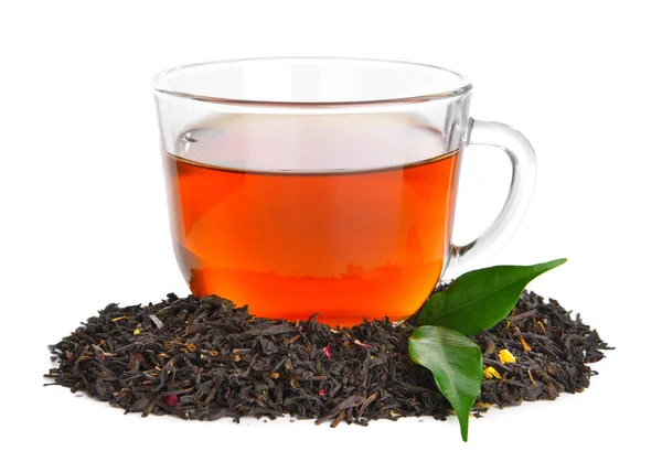 Hojas secas de té negro y taza de bebida aromática sobre fondo blanco — Foto de Stock