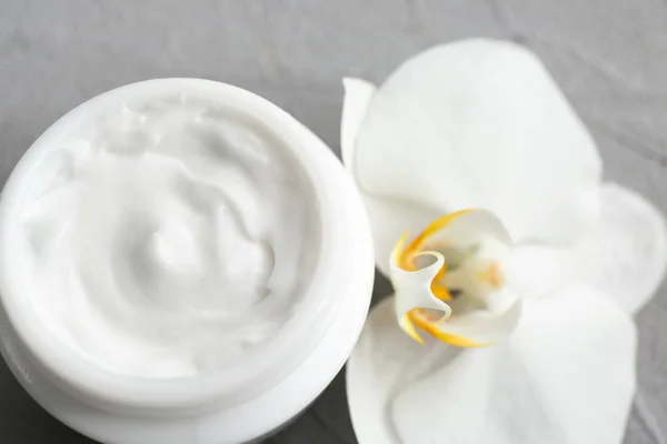 Jar of moisturizing cream and flower on grey background, closeup Royalty Free Stock Photos