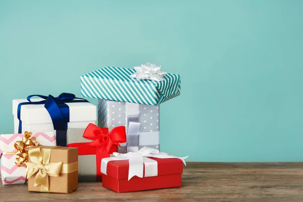 Beautiful gift boxes on table against color background