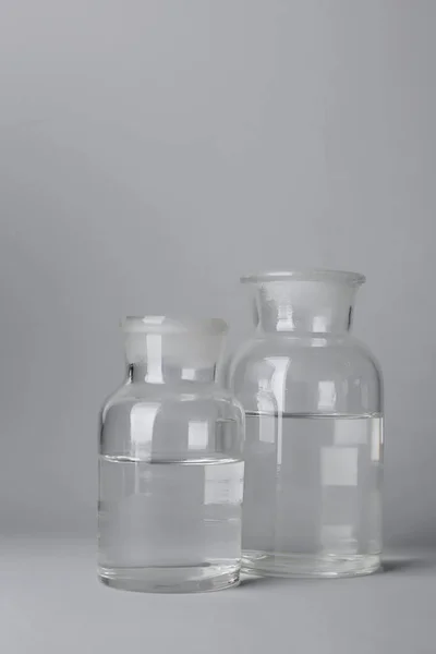 Botellas de vidrio con agua sobre fondo claro — Foto de Stock