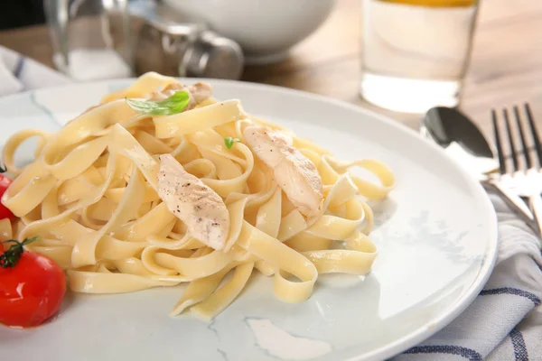 Piatto di deliziosa pasta con filetto di pollo e pomodori in tavola, primo piano — Foto Stock