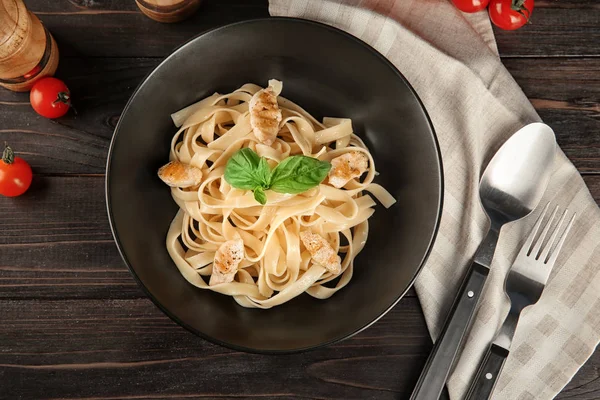 Piatto di gustosa pasta con filetto di pollo sul tavolo di legno, vista dall'alto — Foto Stock