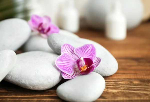Pierres de spa et belles fleurs d'orchidée sur la table en bois, gros plan — Photo