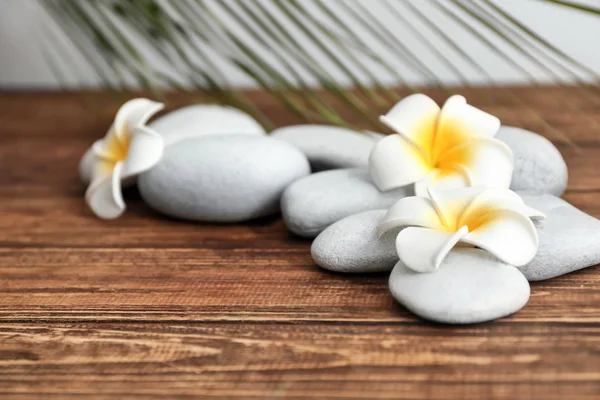 Spa stones and beautiful flowers on wooden background — Stock Photo, Image