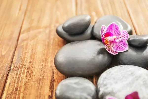 Πέτρες με σπα και όμορφη ορχιδέα λουλούδι ξύλινο φόντο, κοντινό πλάνο — Φωτογραφία Αρχείου