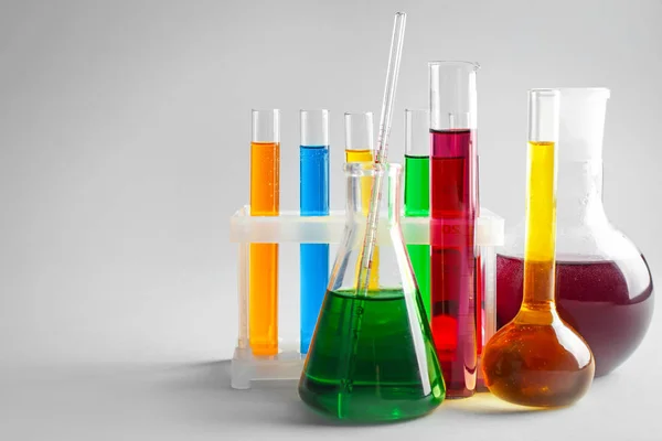 Chemical glassware with colorful samples on light background — Stock Photo, Image