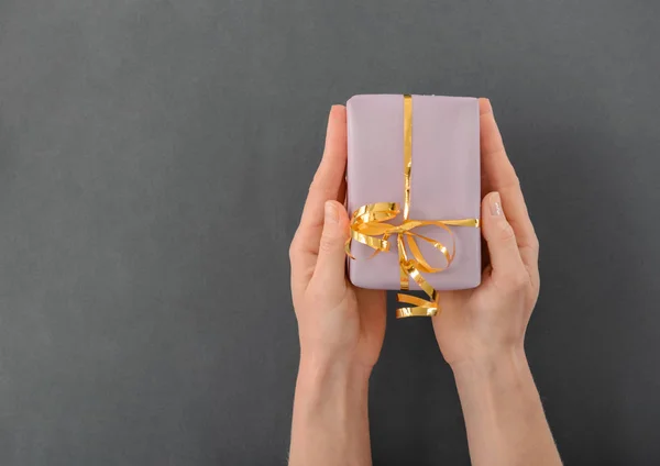 Woman holding gift box on grey background — Stock Photo, Image