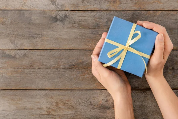 Woman holding gift box on wooden background — Stock Photo, Image