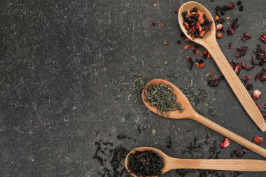 Kaşık ile farklı tip-in kuru çay yaprakları gri arka plan üzerinde