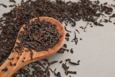 Gri arka plan üzerine kaşık kuru siyah çay yaprakları